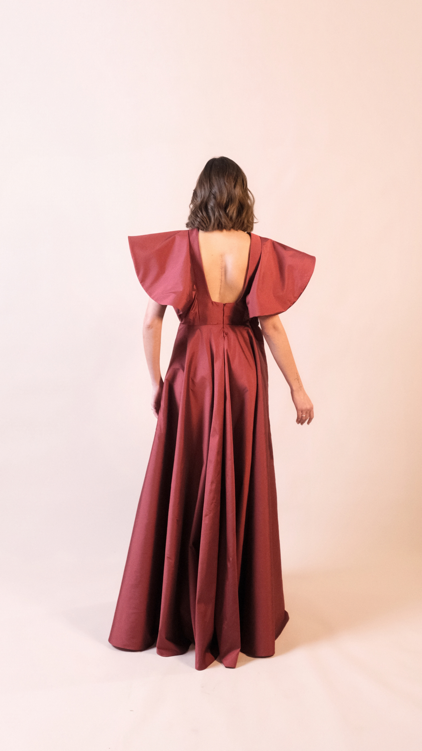 Vestido de festa longo preto Em Dó Menor em tafetá, com decote canoa, mangas estruturadas e saia ampla em godê duplo.
