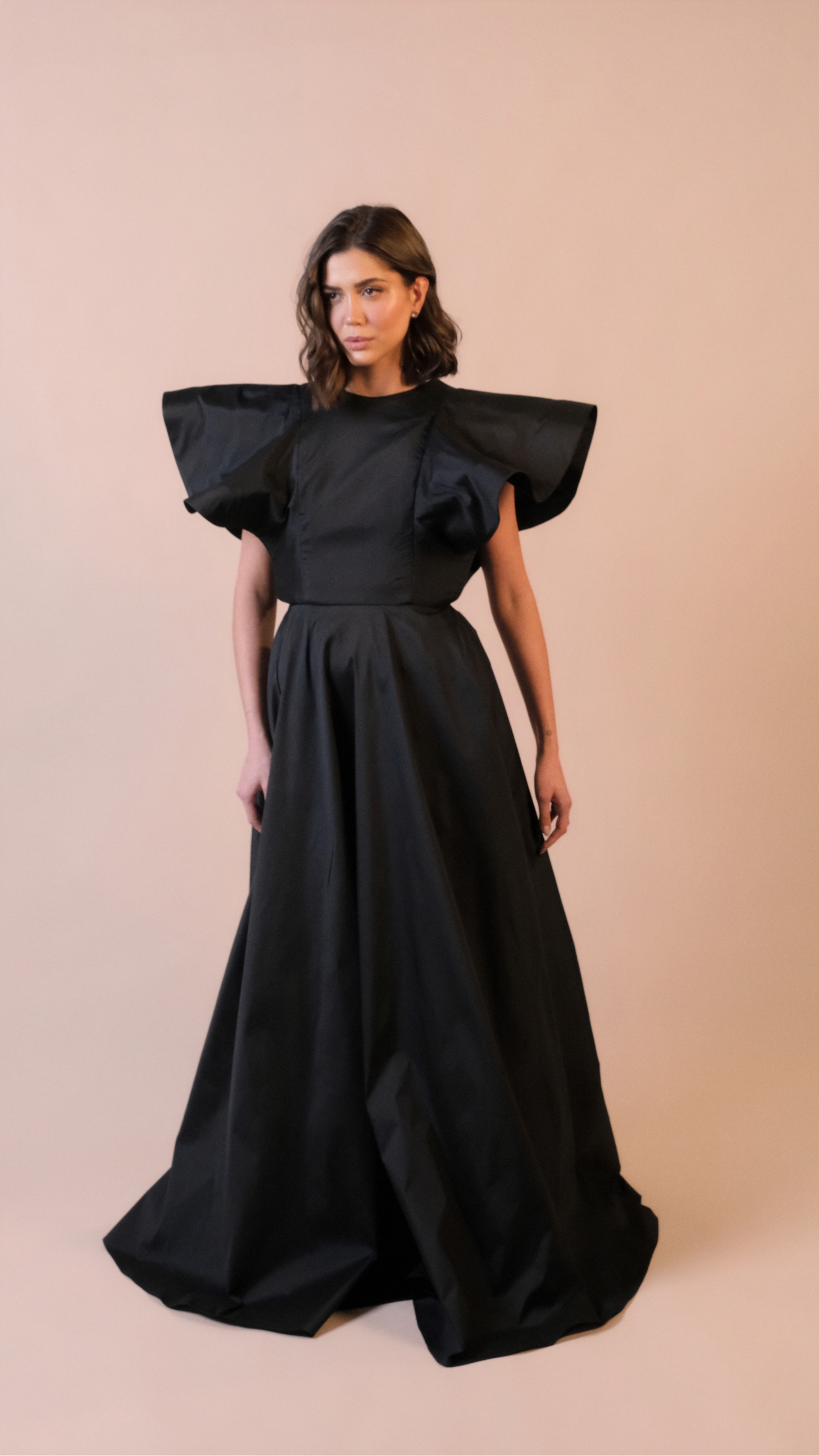 Vestido de festa longo preto Em Dó Menor em tafetá, com decote canoa, mangas estruturadas e saia ampla em godê duplo.