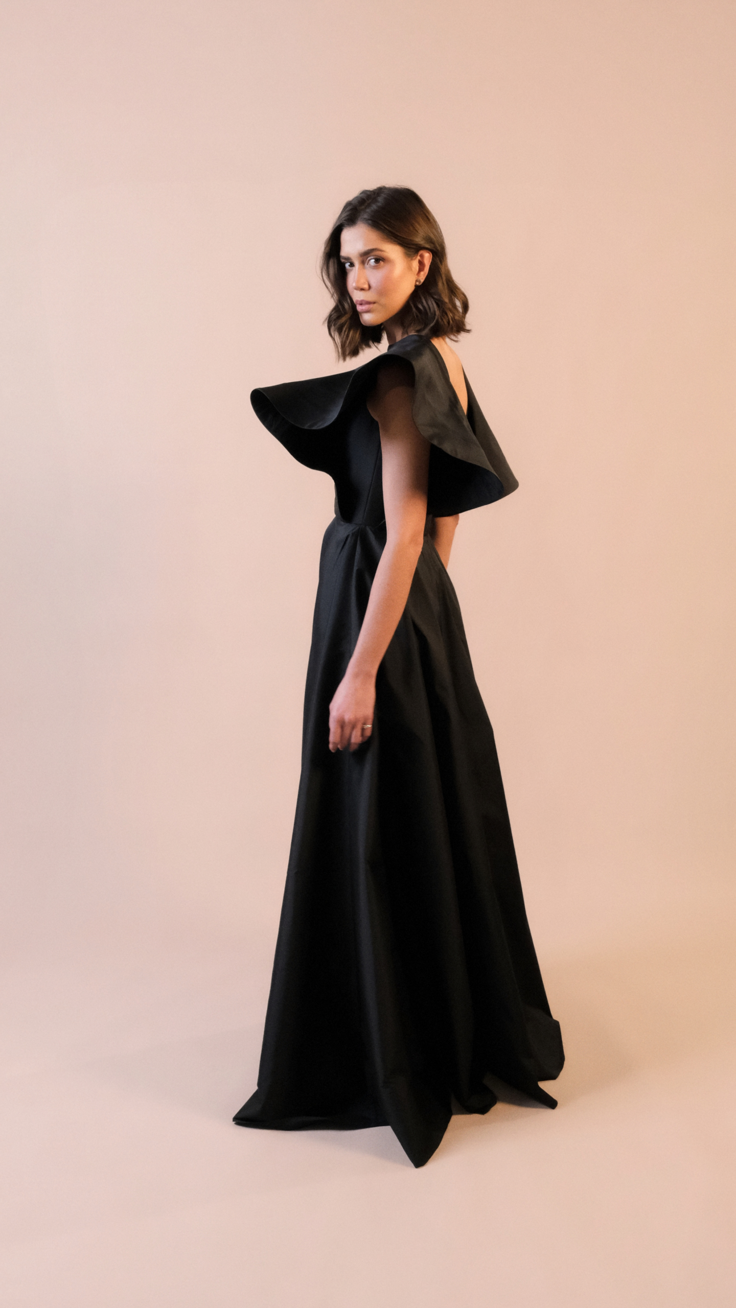 Vestido de festa longo preto Em Dó Menor em tafetá, com decote canoa, mangas estruturadas e saia ampla em godê duplo.