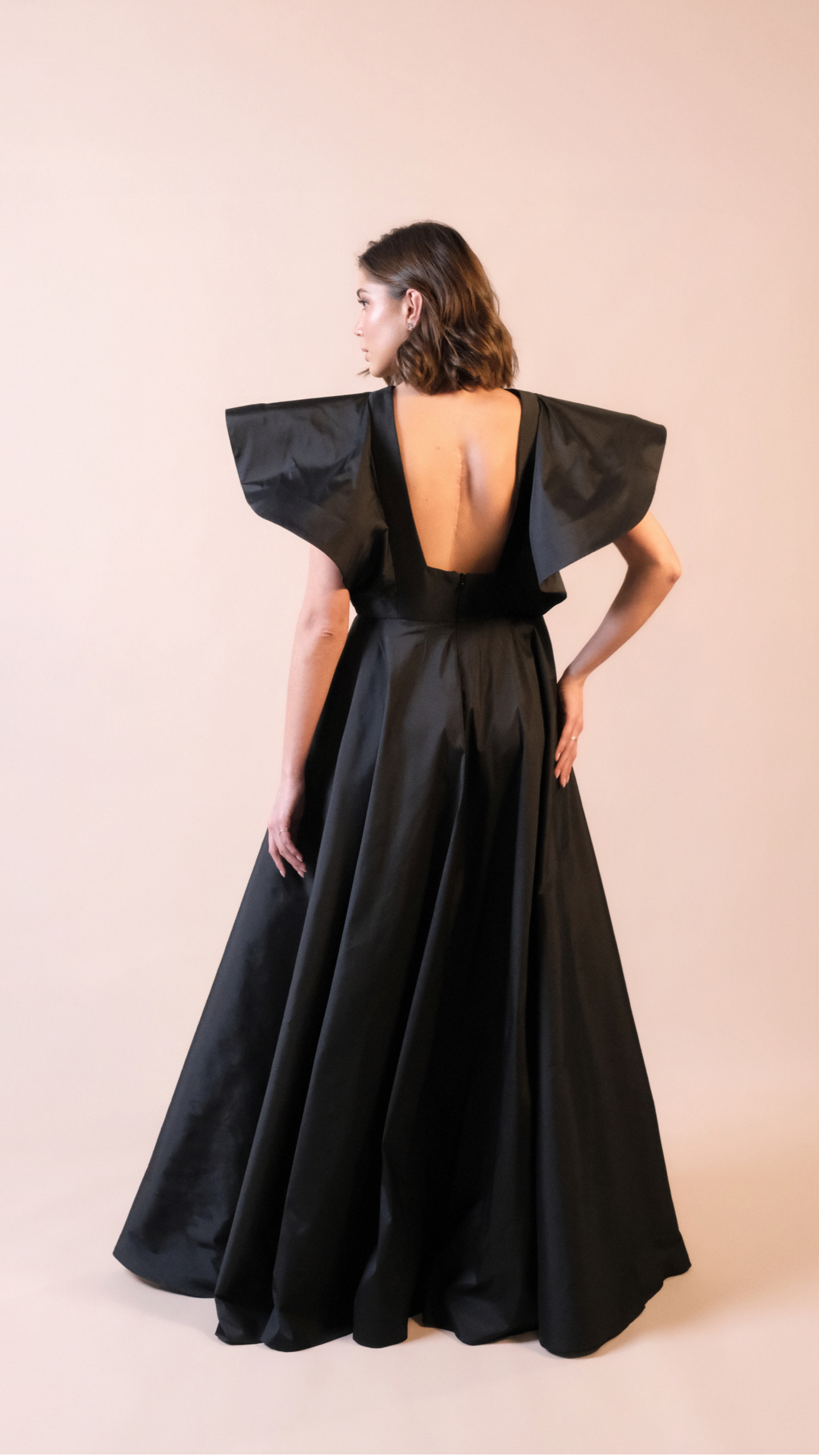 Vestido de festa longo preto Em Dó Menor em tafetá, com decote canoa, mangas estruturadas e saia ampla em godê duplo.